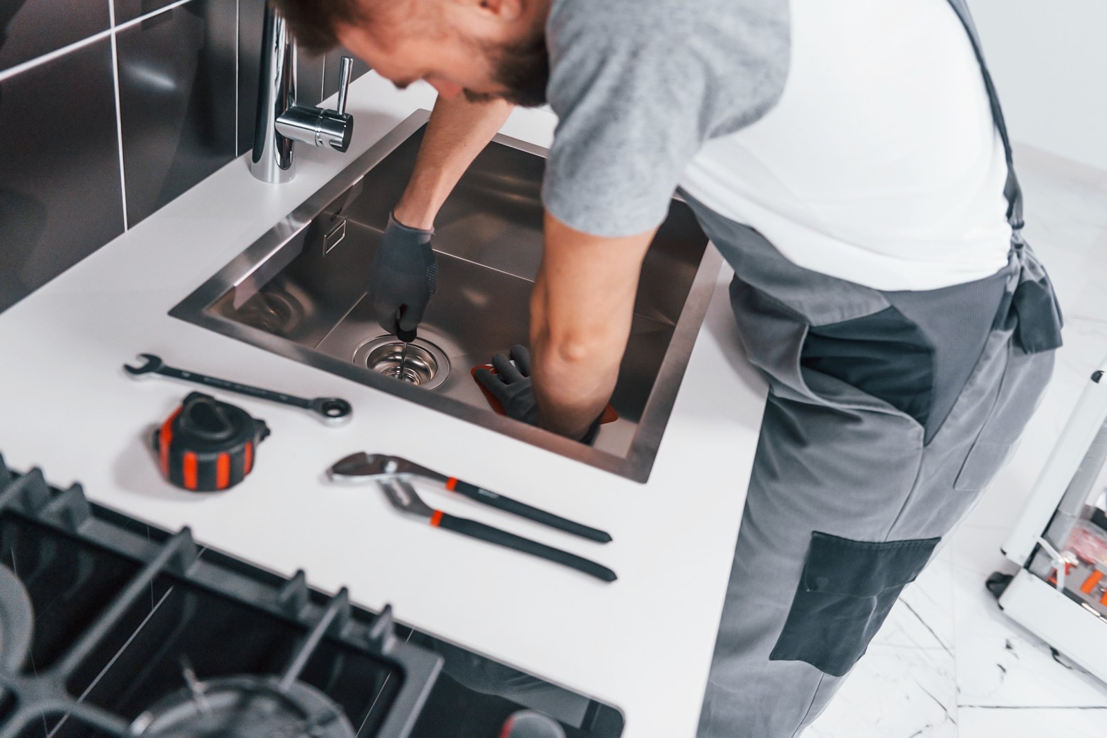 Illustrative photo of a tradesperson working on a kitchen sink drain